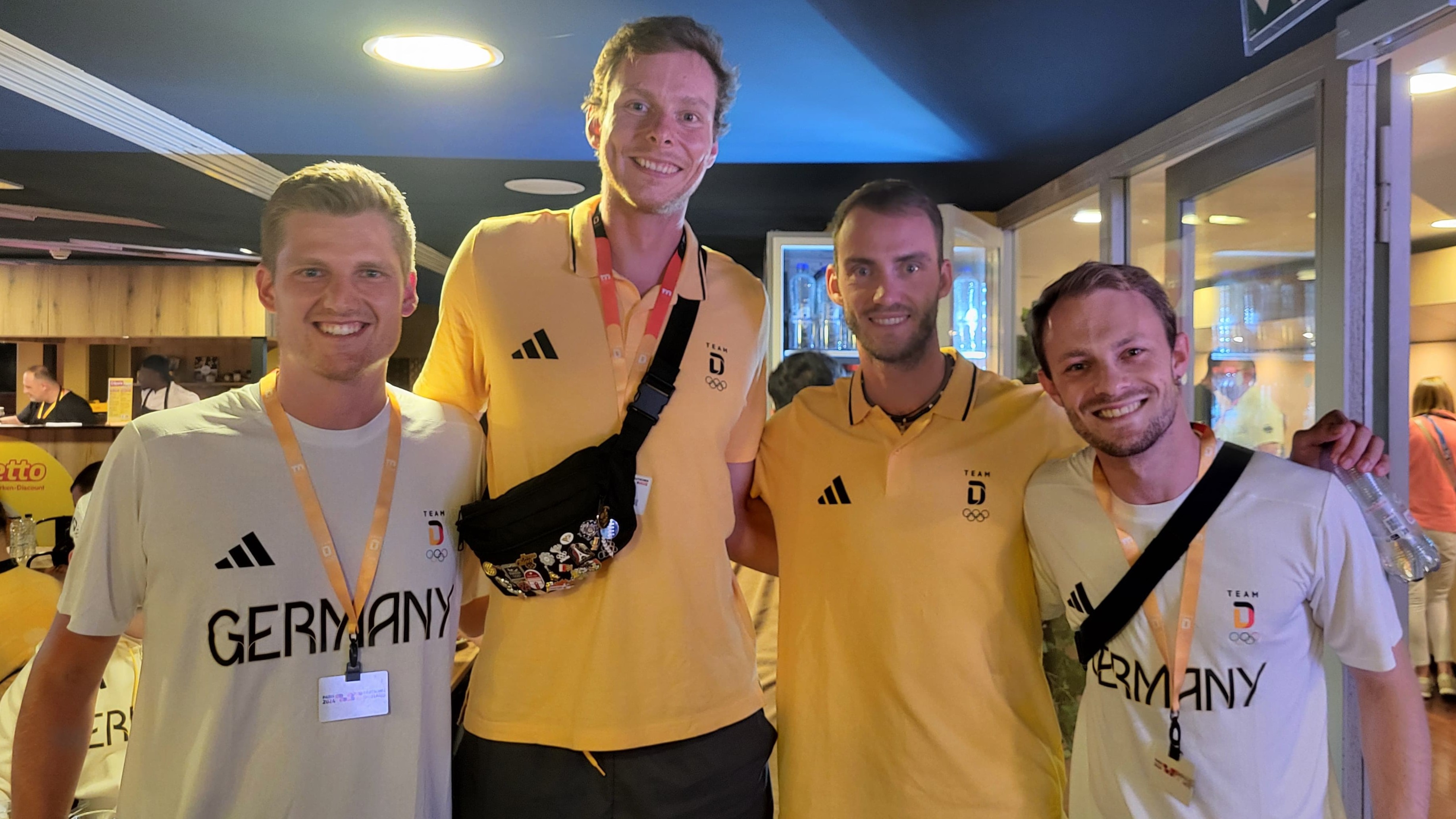 Olympia-Volunteer Lukas Adams mit den deutschen Beachvolleyballern Nils Ehlers und Clemens Wickler